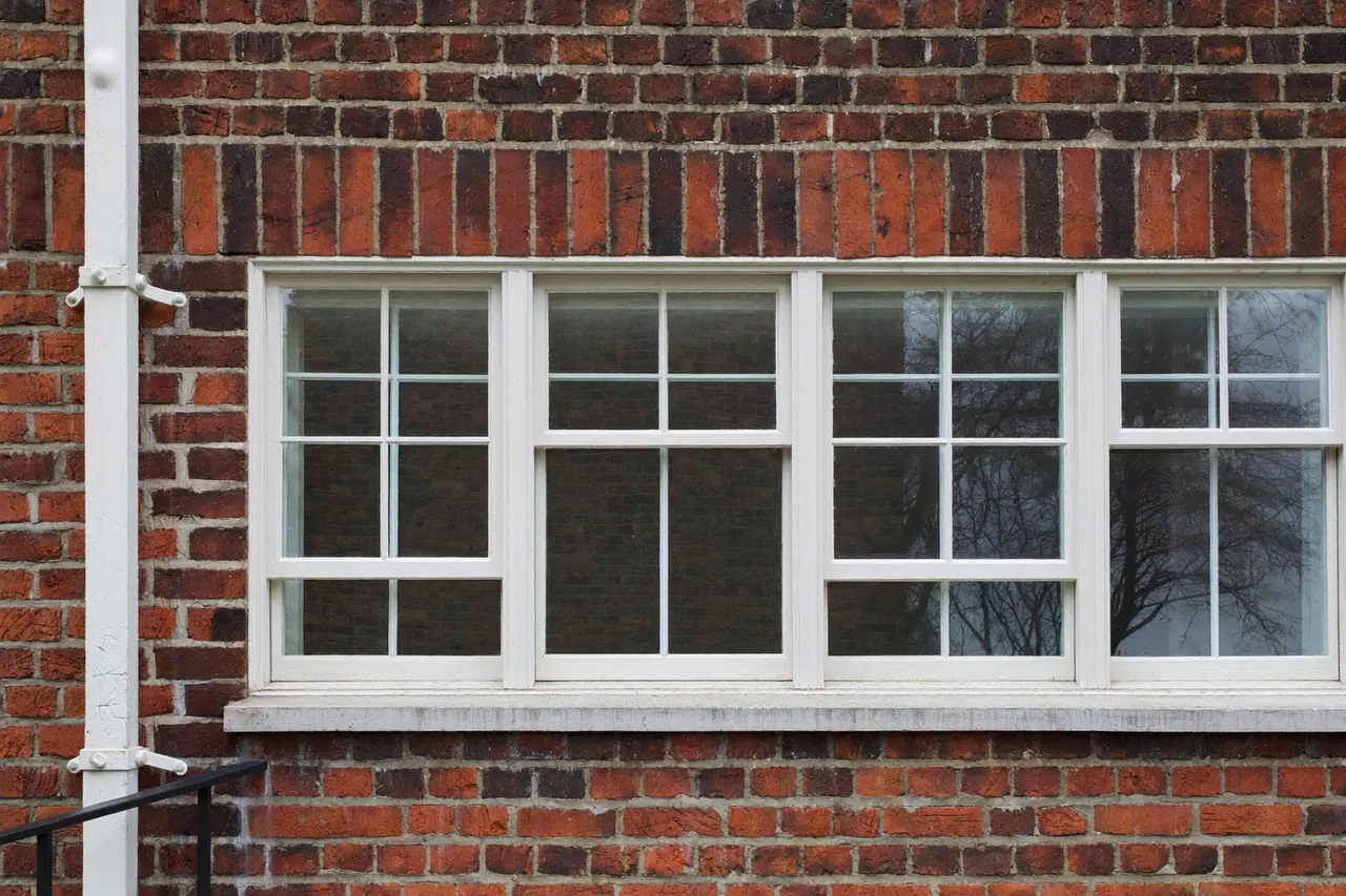 A row of new white sash windows on a period brick home